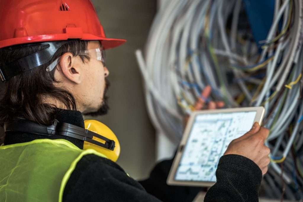 Worker reading electrician plans on digital tablet
