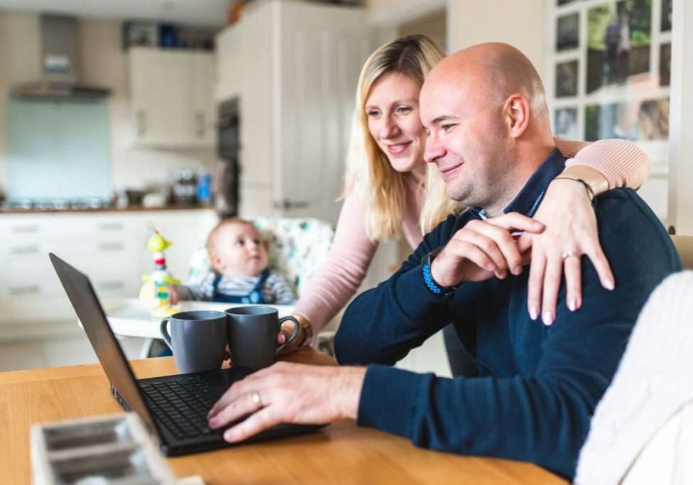 Young family working from home using computer and planning to purchase a Heat Pump Water Heater. 
