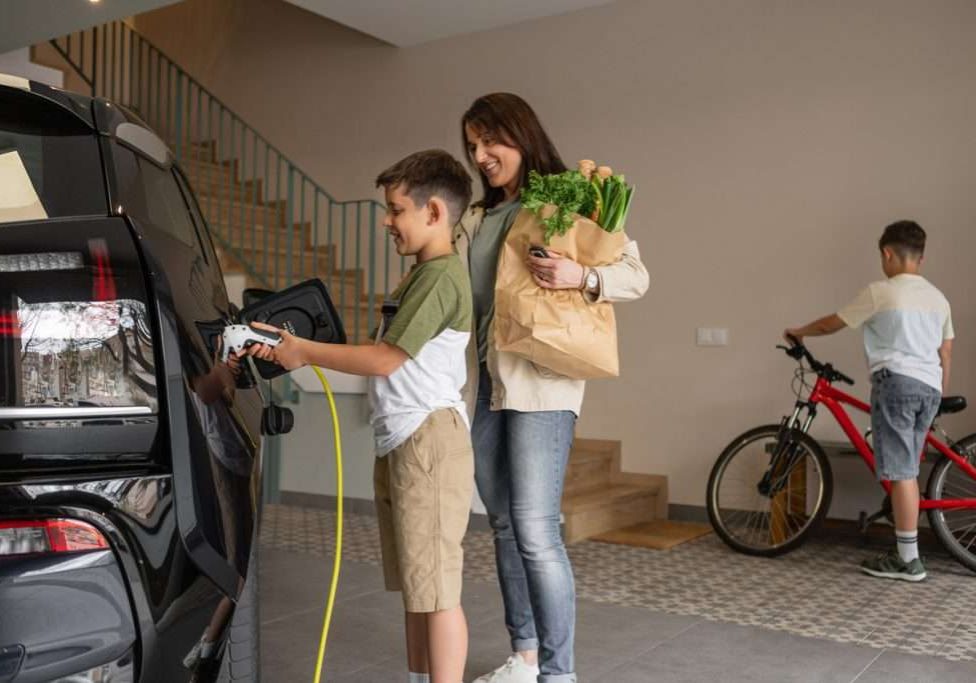 Smiling mother and son charging electric car at home.