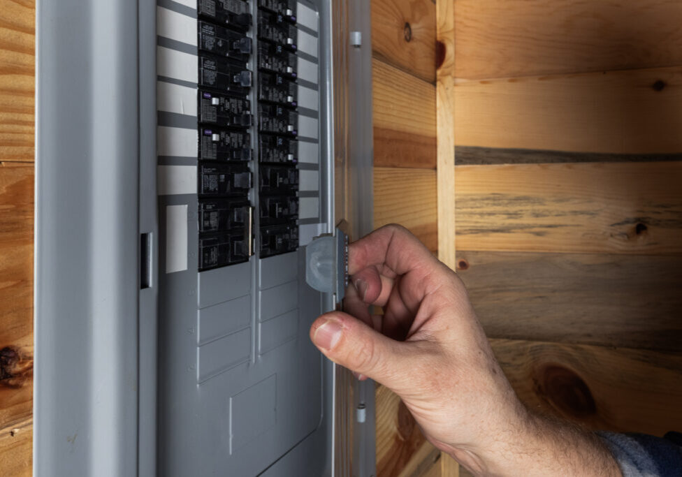 Close up of a home owner inspecting the electrical panel of their home. 