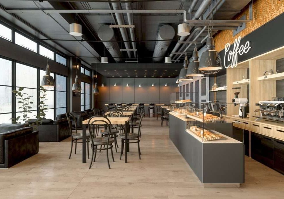 Empty Coffee Shop Interior With Wooden Tables, Coffee Maker, Pastries And Pendant Lights