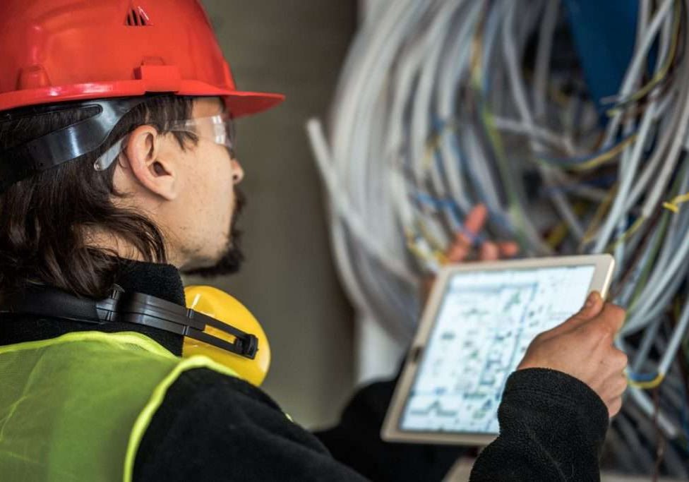 Worker reading electrician plans on digital tablet