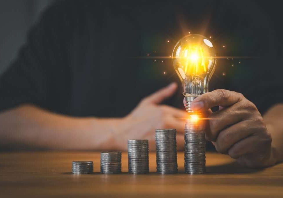 Adult man hand holding a light bulb putting on money stack. New ideas for savings money, taxes, retirement, working, small business, finance, investment, financial planning, and financial concept.